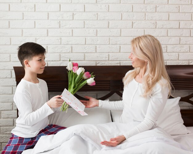 Side view son offering flowers to mom