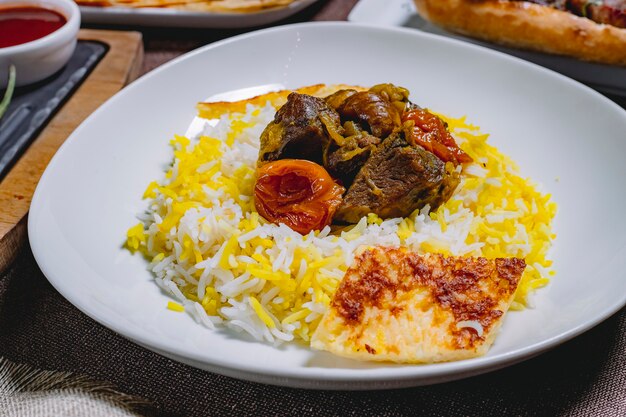 Side view sour pilaf sour fried meat with onion chestnuts dried fruits and cake on a plate