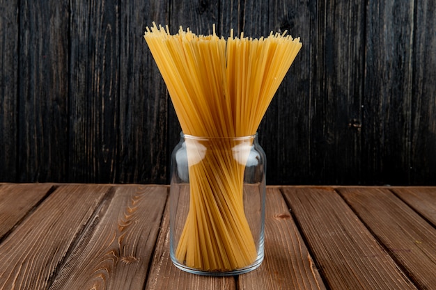 Вид сбоку макароны спагетти в банке на деревянном фоне