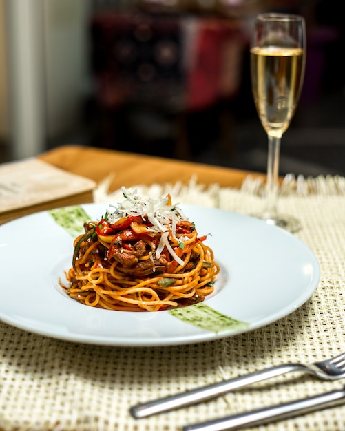 Free photo side view spaghetti with meat and grated cheese and a glass of champagne