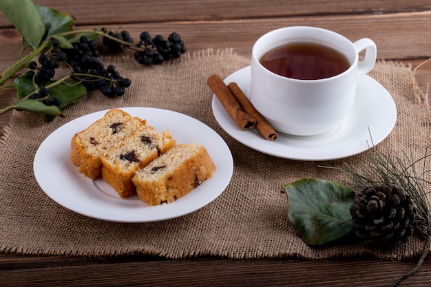 Side view of sponge cake slices on a plate with a cup of black tea on rustic