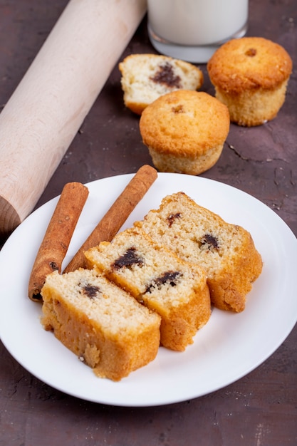 Side view of sponge cake slices with cinnamon sticks on a white plate