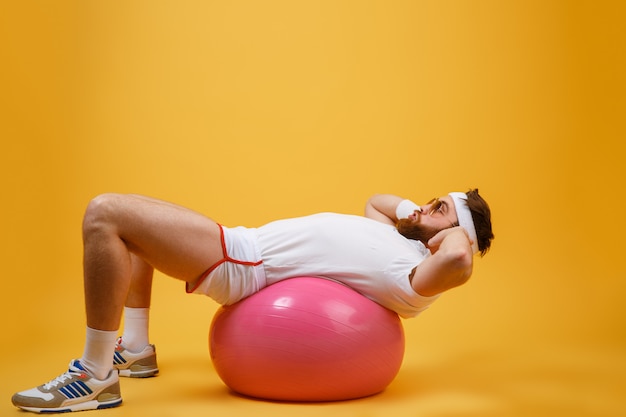 Side view of sportsman lying on fitness ball