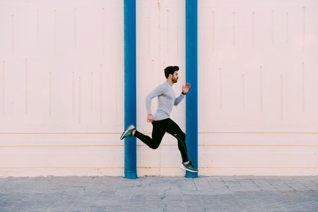 Side view sportsman running near wall