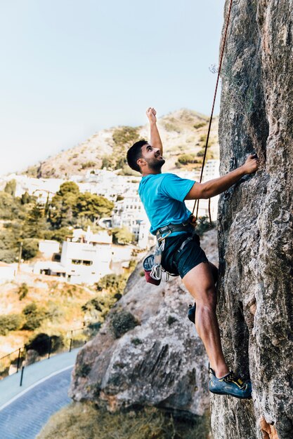 Side view of sporty man climbing on rock