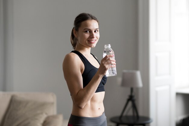 Side view of sporty woman holding bottle of water