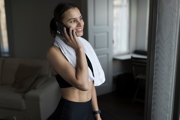 Side view of sporty woman talking her smartphone