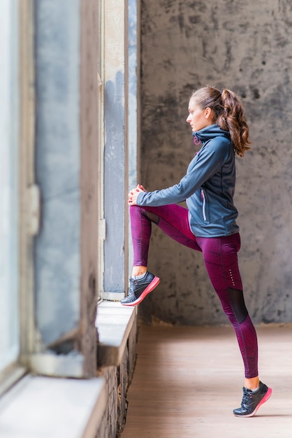 Side view of a sporty young woman looking through window