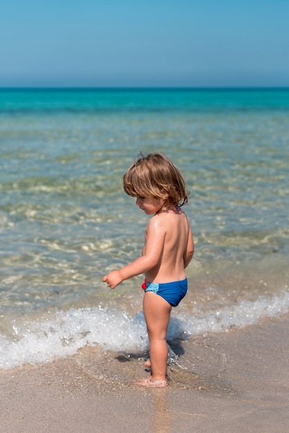Боковой вид стоящего ребенка на пляже