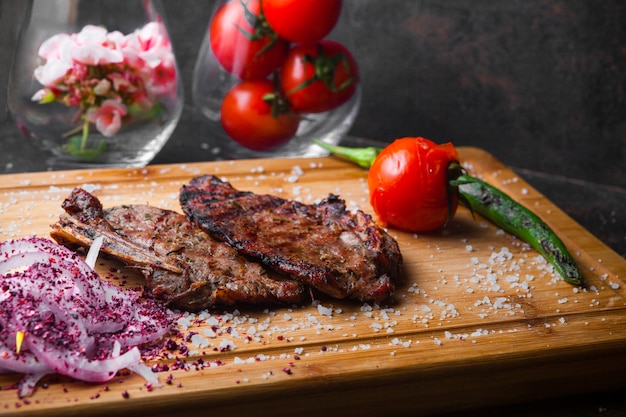 Side view steak with tomato and onion in steak board