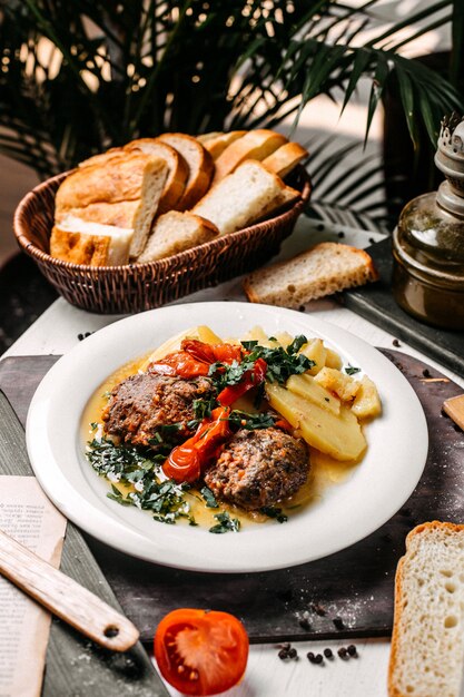 Side view of stewed meat potatoes and herbs on a white plate