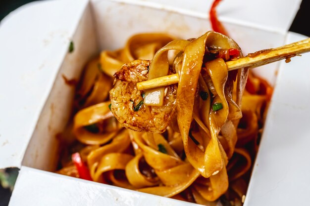 Side view stir-fried noodles with grilled shrimps sauce spring onion and bell pepper