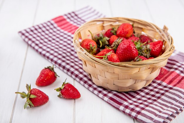 Side view of strawberries in basket on plaid cloth and wood