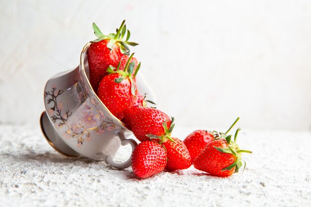 Side view strawberries in coffee cup on white textured background. horizontal copy space for text