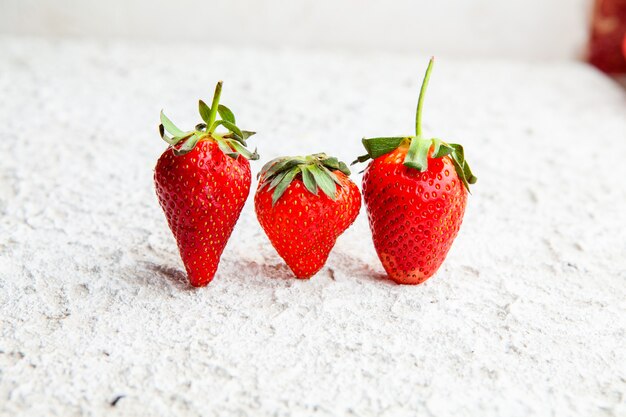 Side view strawberries on white textured background. horizontal