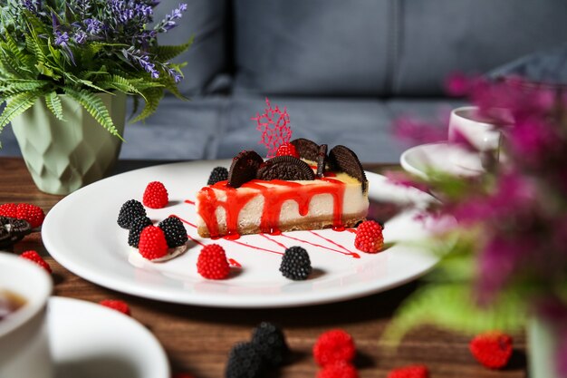 Side view strawberry cheesecake with chocolate chip cookies and blackberry and raspberry marmalade on a plate