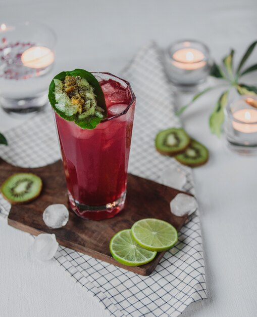 Side view of strawberry cocktail with kiwi and lime on a wooden board on the table