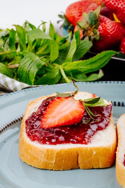 Side view strawberry toast white bread with strawberry jam and mint on the table
