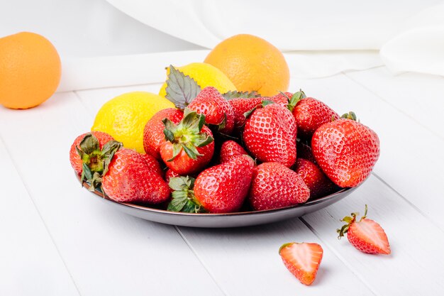 Side view strawberry with lemon basil and orange on white background