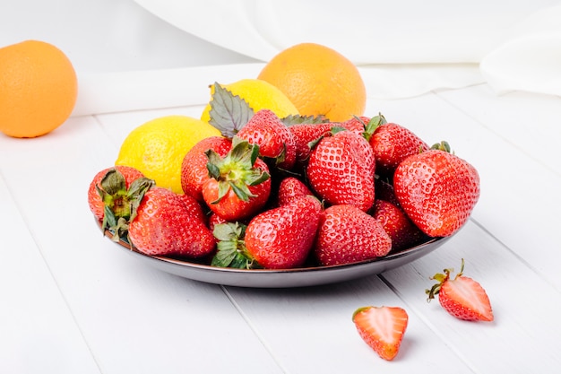 Side view strawberry with lemon basil and orange on white background