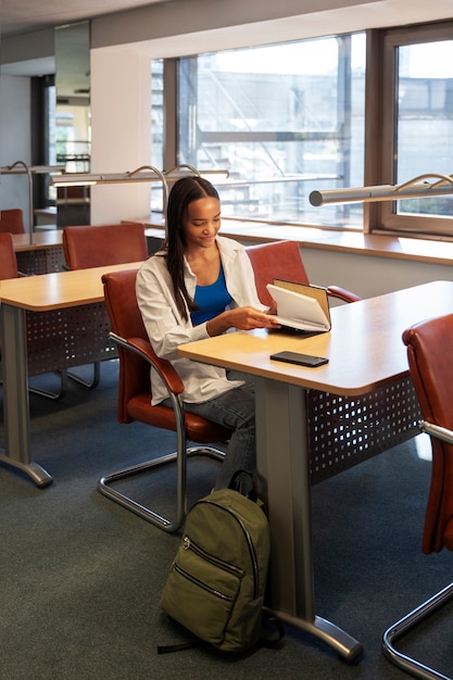 Foto gratuita studente di vista laterale che studia con il taccuino