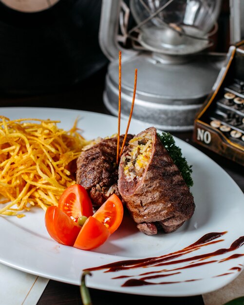 Side view of stuffed meat cutlet with vegetables tomato and fried potato