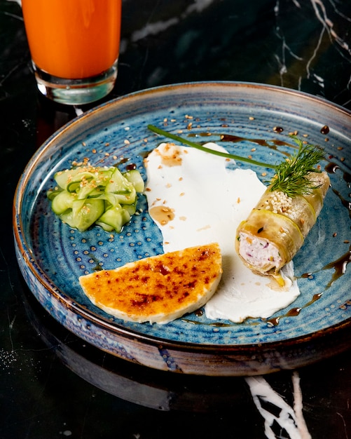 Вид сбоку фаршированный цуккини с ломтиком сыра и огурца на синюю тарелку