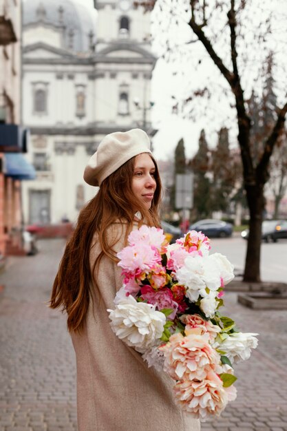 Side view of stylish woman outdoors holding bouquet of flowers in the spring