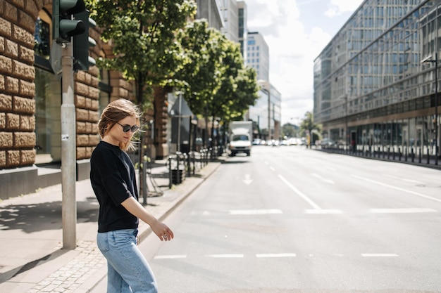 La vista laterale della donna alla moda che cammina sulla strada