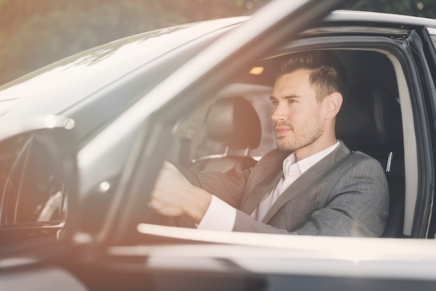 Side view of stylish young male driver in the car