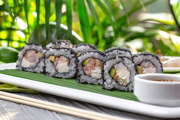 Side view sushi rolls with shrimps with soy sauce on a plate