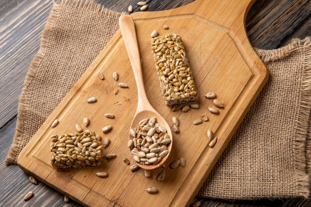 Side view of sweet kozinaki of sunflower seeds with a wooden spoon on wooden board