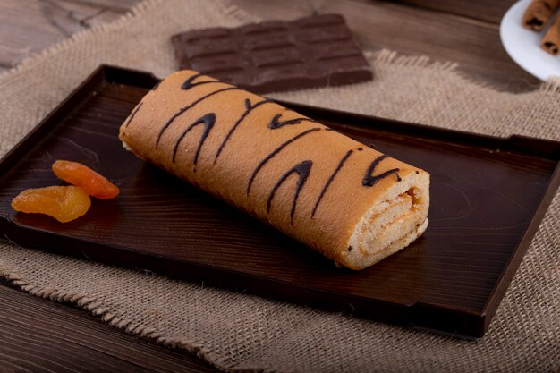 Side view of swiss roll with apricot jam on a black board
