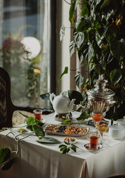 Free photo side view of a table served with tea and nuts and dried fruits in a plate