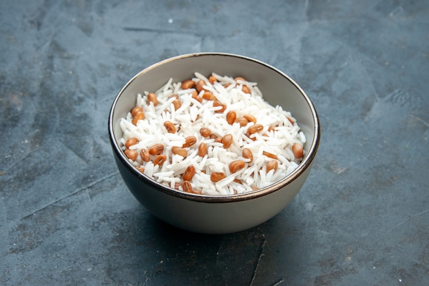 Side view of tasty rice meal with beans in a brown small pot on blue background