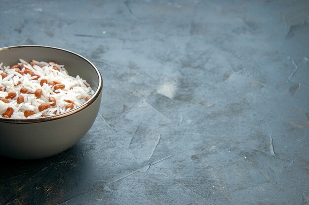 Side view of tasty rice meal with beans in a brown small pot on blue table