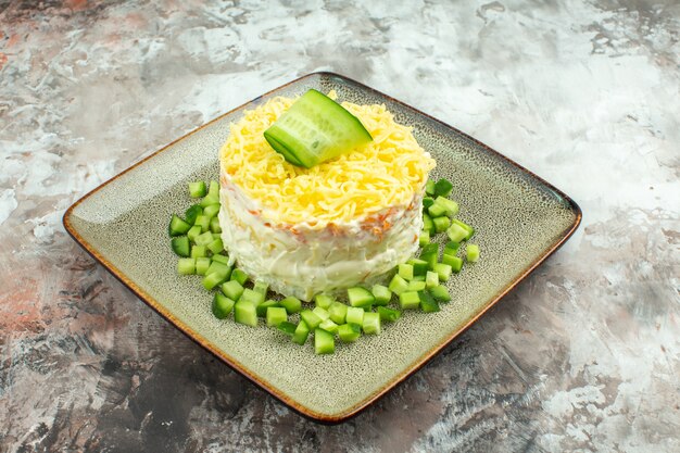 Side view of tasty salad served with chopped cucumber on mixed color background