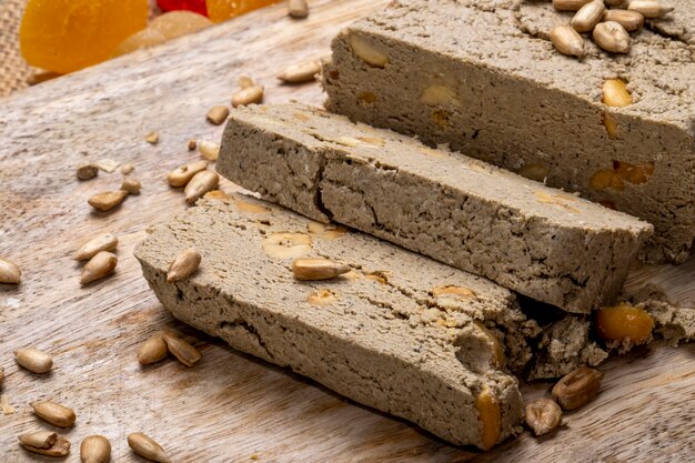 Side view of tasty slices of halva with sunflower seeds on rustic
