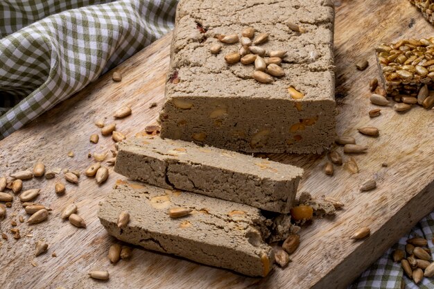 Side view of tasty slices of halva with sunflower seeds on a wooden board