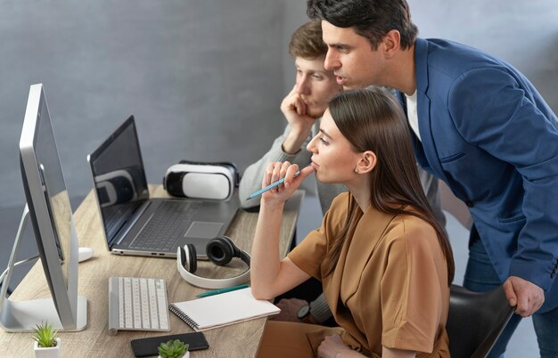 Вид сбоку команды профессионалов, работающих с компьютером и ноутбуком