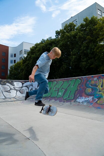 Free photo side view teen doing trick on skateboard