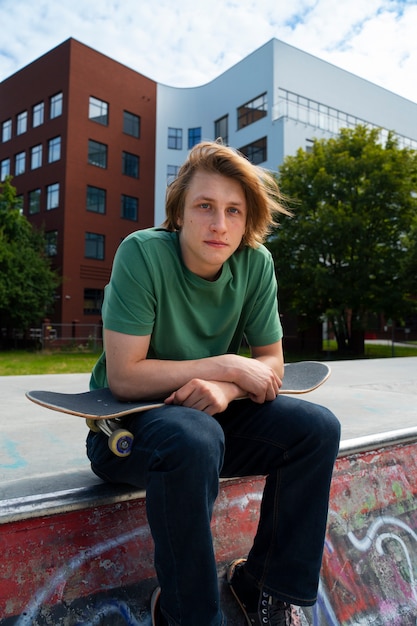 Side view teen sitting with skateboard