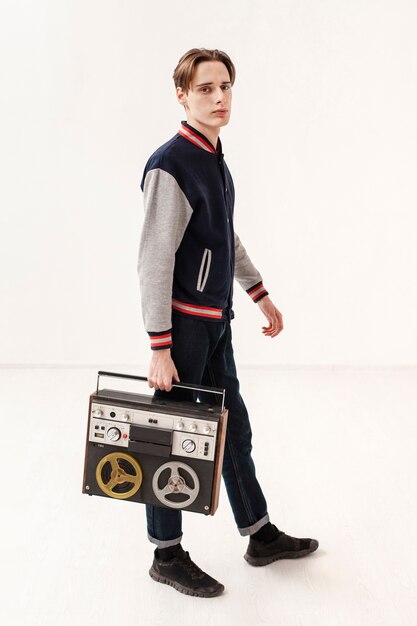 Free photo side view teenage boy holding cassette