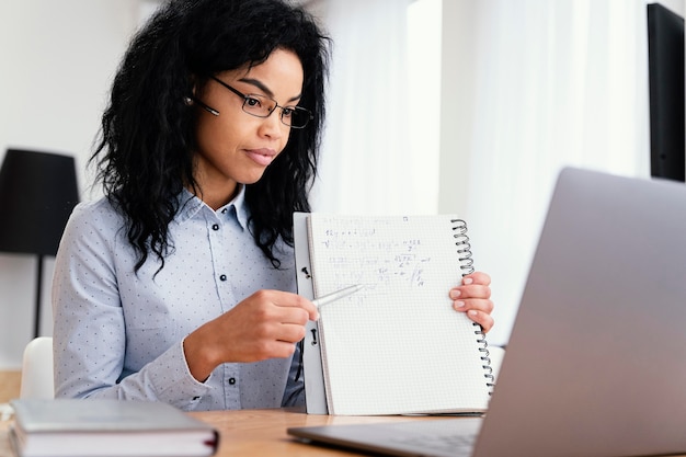 Side view of teenage girl at home during online school with laptop and notebook