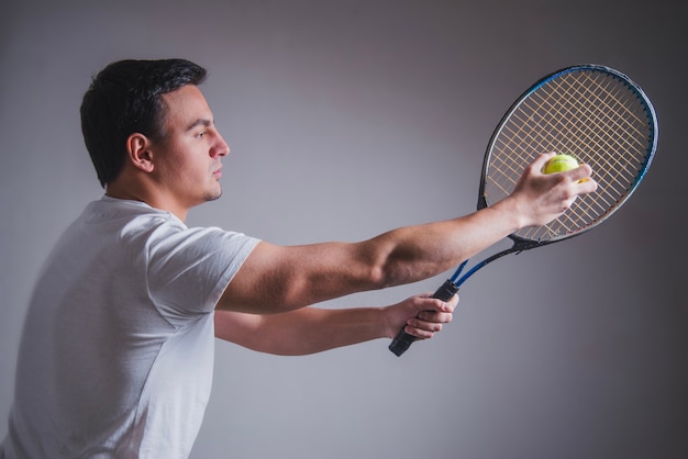 ラケットとボールでポーズを取っているテニスプレーヤーの側面図