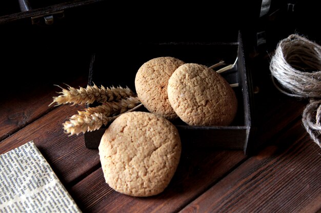 Side view three oatmeal cookies with thread and newspaper