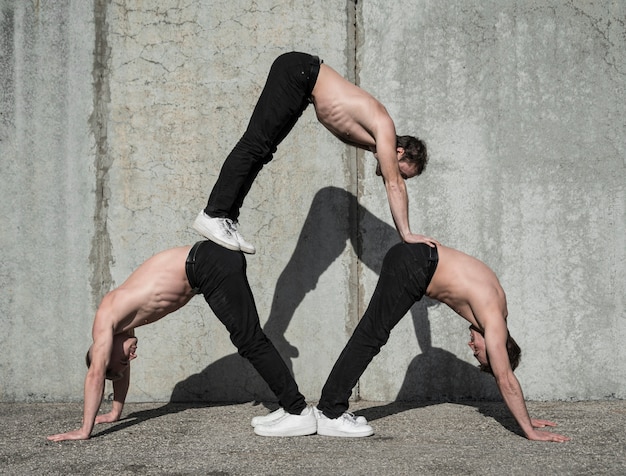 Side view of three shirtless hip hop artists practicing dance routine