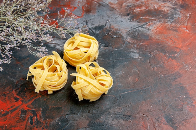 Side view of three uncooked spaghetti portions on mixed color table