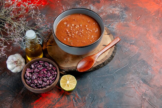 混合色のテーブルの木製トレイ豆油瓶の青いボウルにトマトスープの側面図