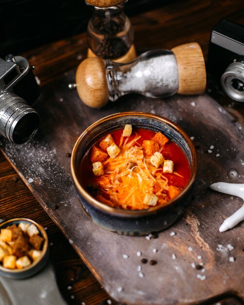Вид сбоку томатный суп с сыром и тостами в миску